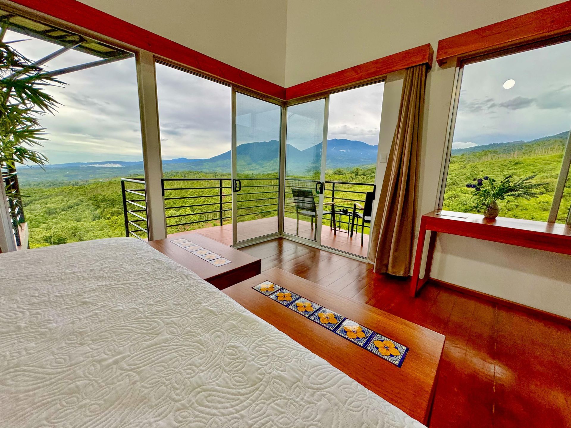A bedroom with a large bed and a balcony with a view of the mountains.
