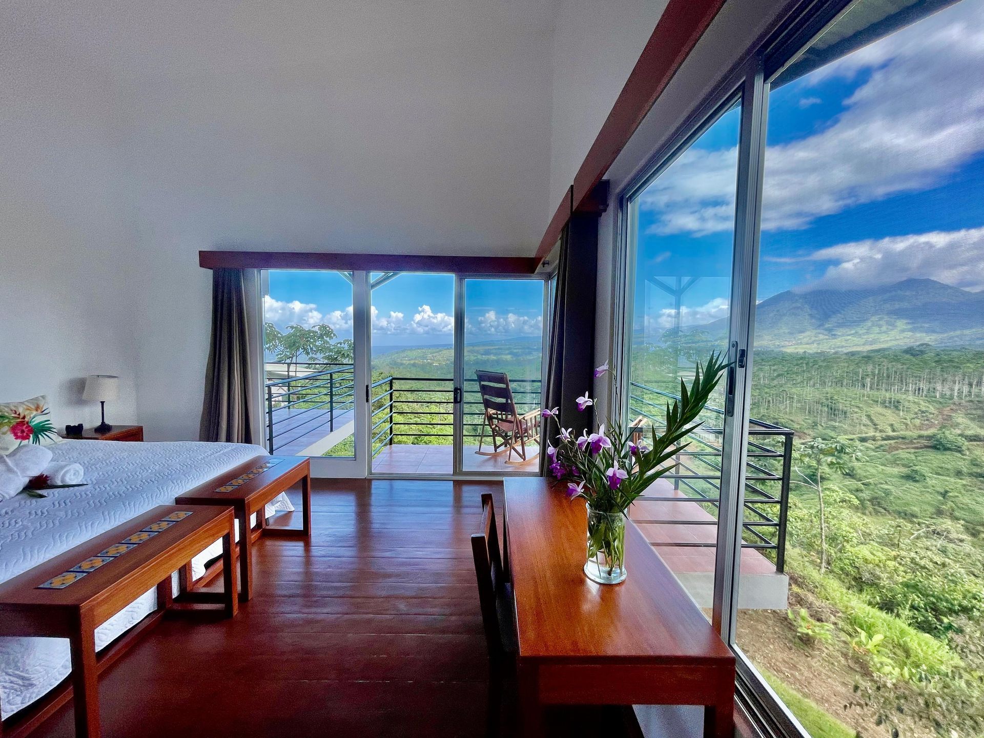 Two rocking chairs are sitting on a balcony overlooking mountains