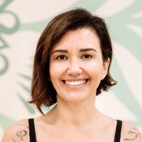 A woman with a tattoo on her shoulder is smiling for the camera.