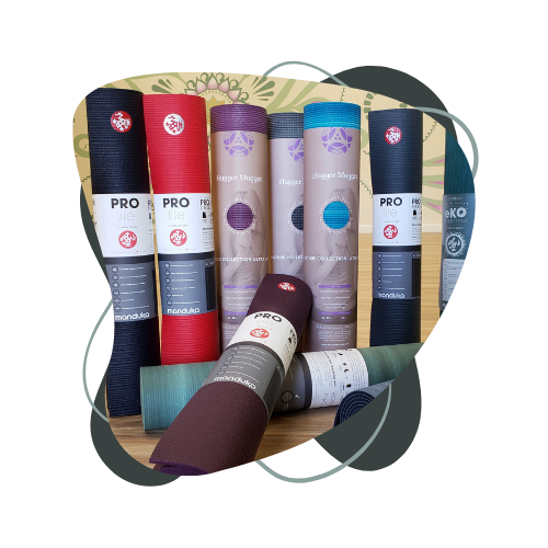 A bunch of yoga mats are stacked on top of each other on a wooden table.