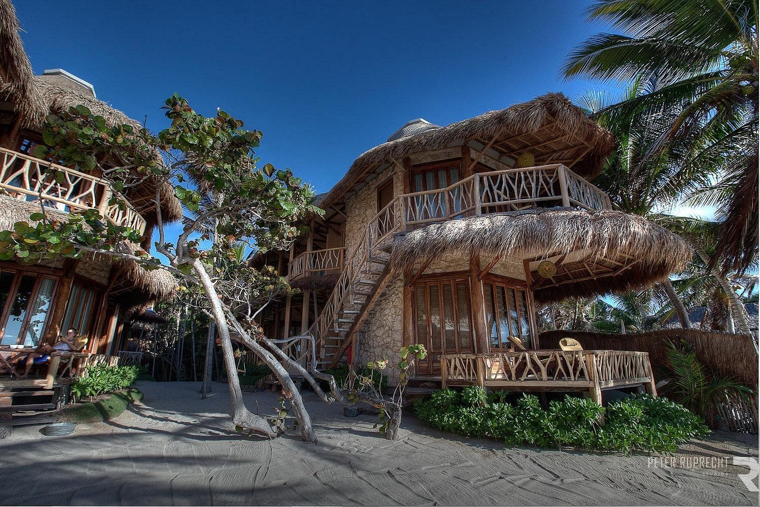 A bedroom with a large bed and a balcony with a view of the mountains.
