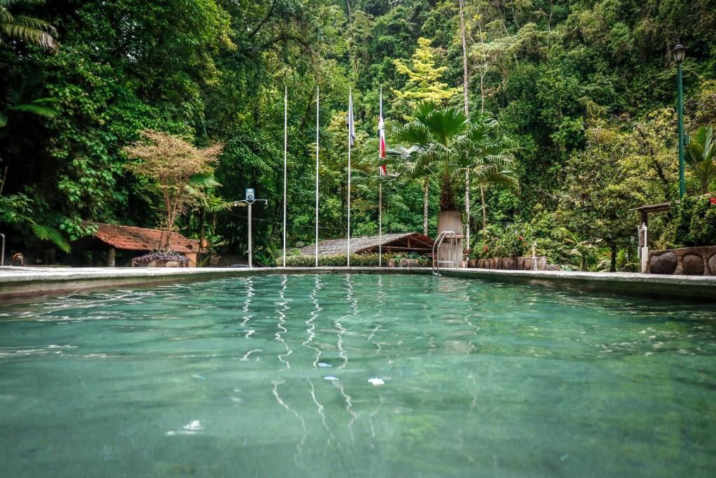A bedroom with a large bed , a lamp , a table and chairs.
