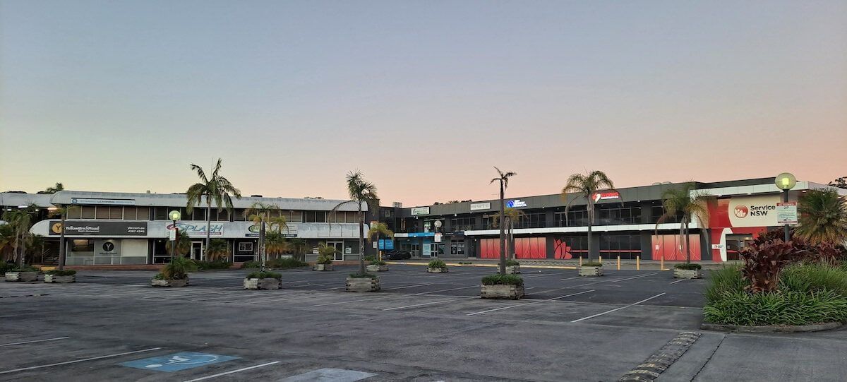 An Empty Parking Lot With Palm Trees in Front of a Building — Maratustech In Erina, NSW