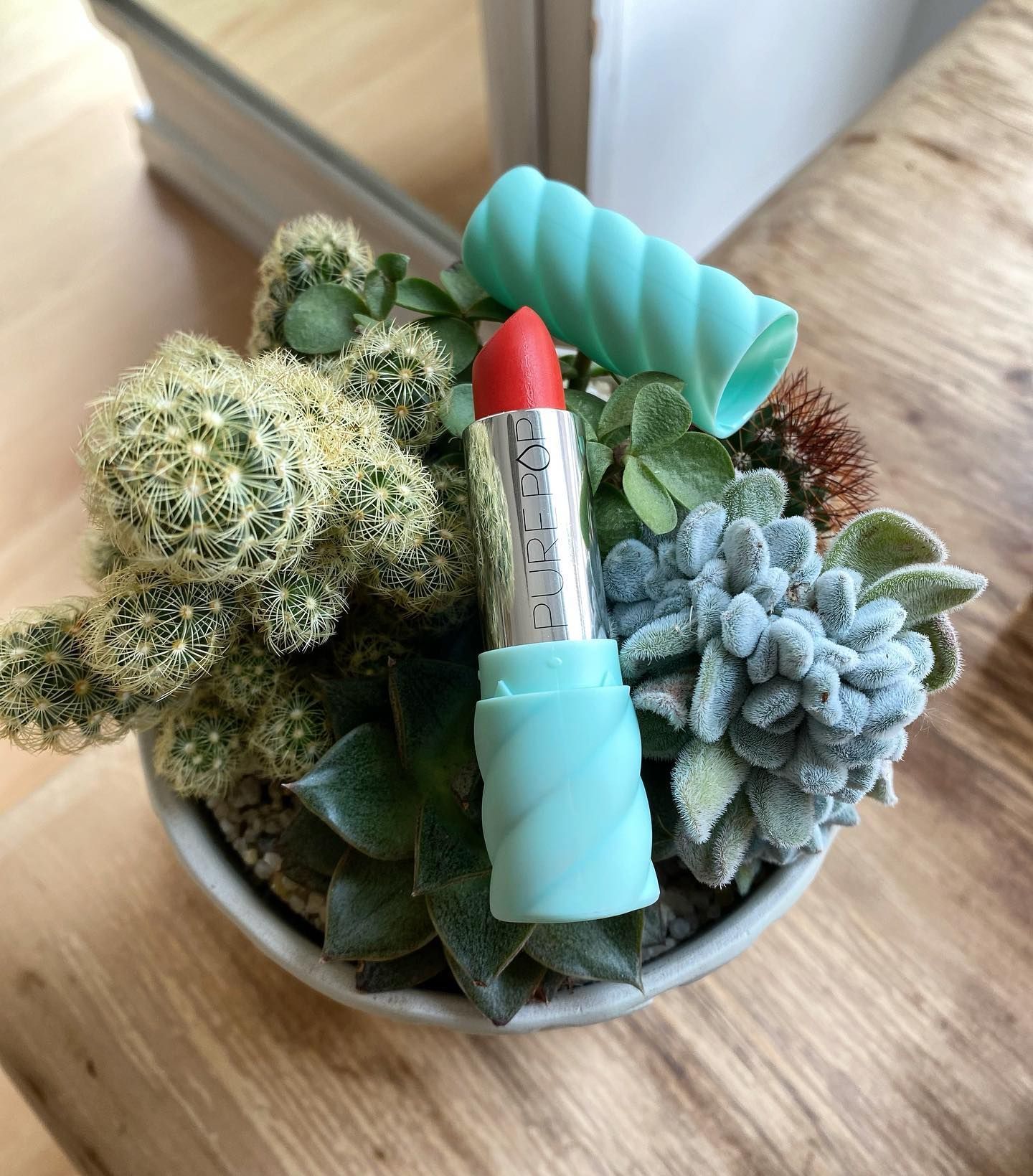 Una pianta in vaso con dentro un rossetto rosso