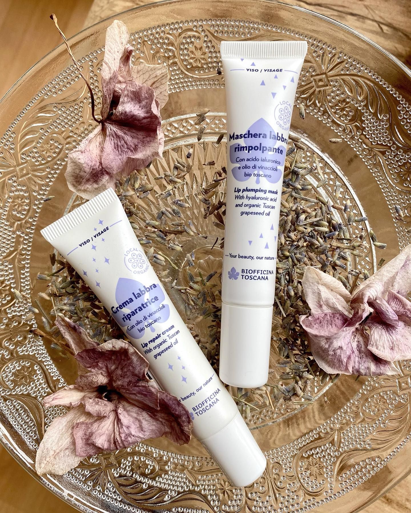Due tubi di balsamo per le labbra sono posizionati sopra una lastra di vetro.