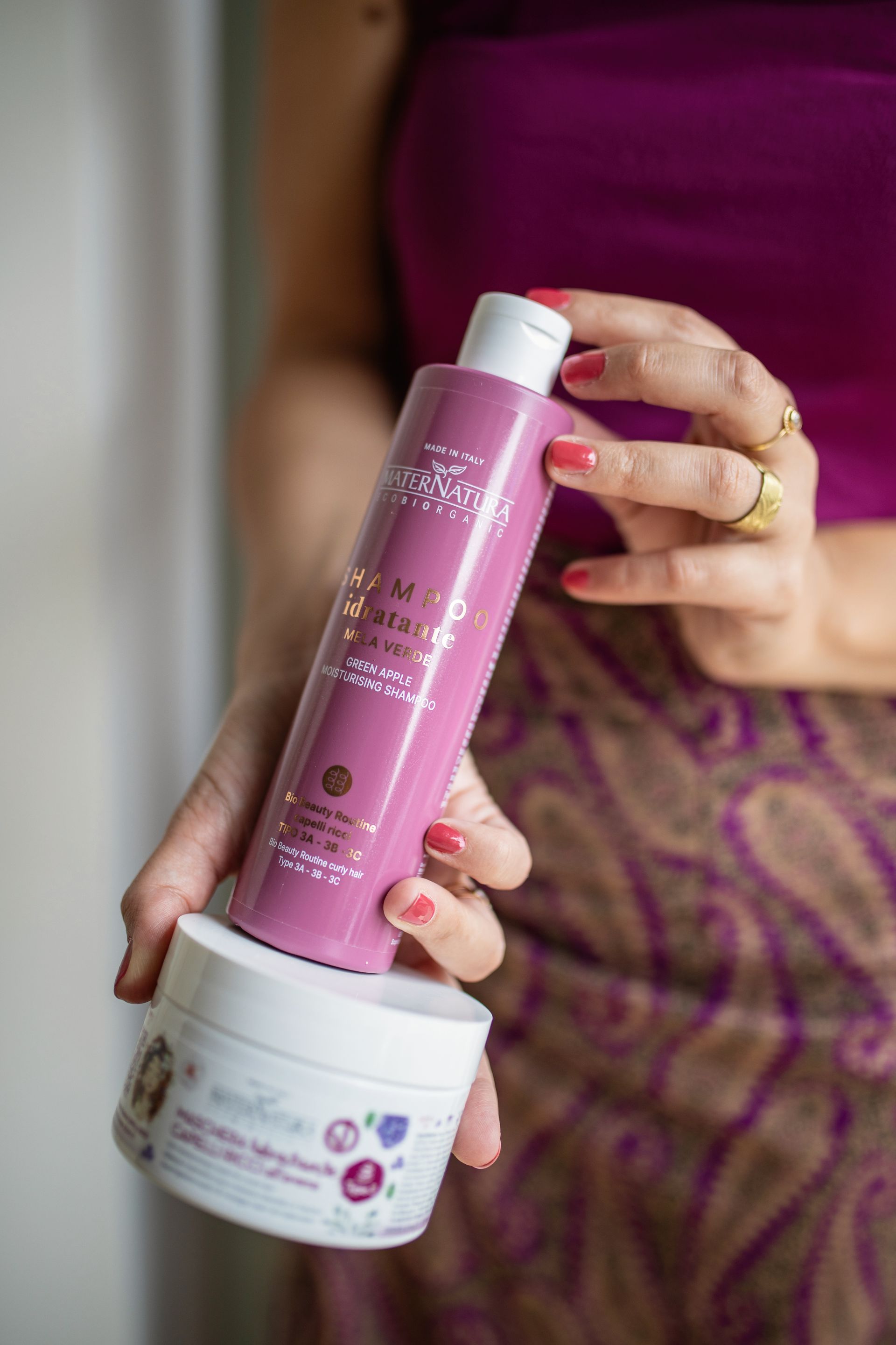 Una donna tiene in mano una bottiglia di shampoo e un barattolo di maschera.