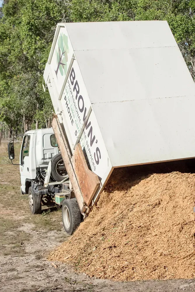A Truck from Brown's Landscaping Dumping Wood Chips — Brown's Professional Tree Service In Pie Creek, QLD