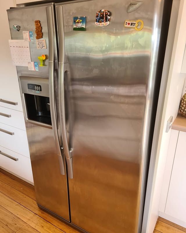 A stainless steel refrigerator with a water dispenser is in a kitchen.