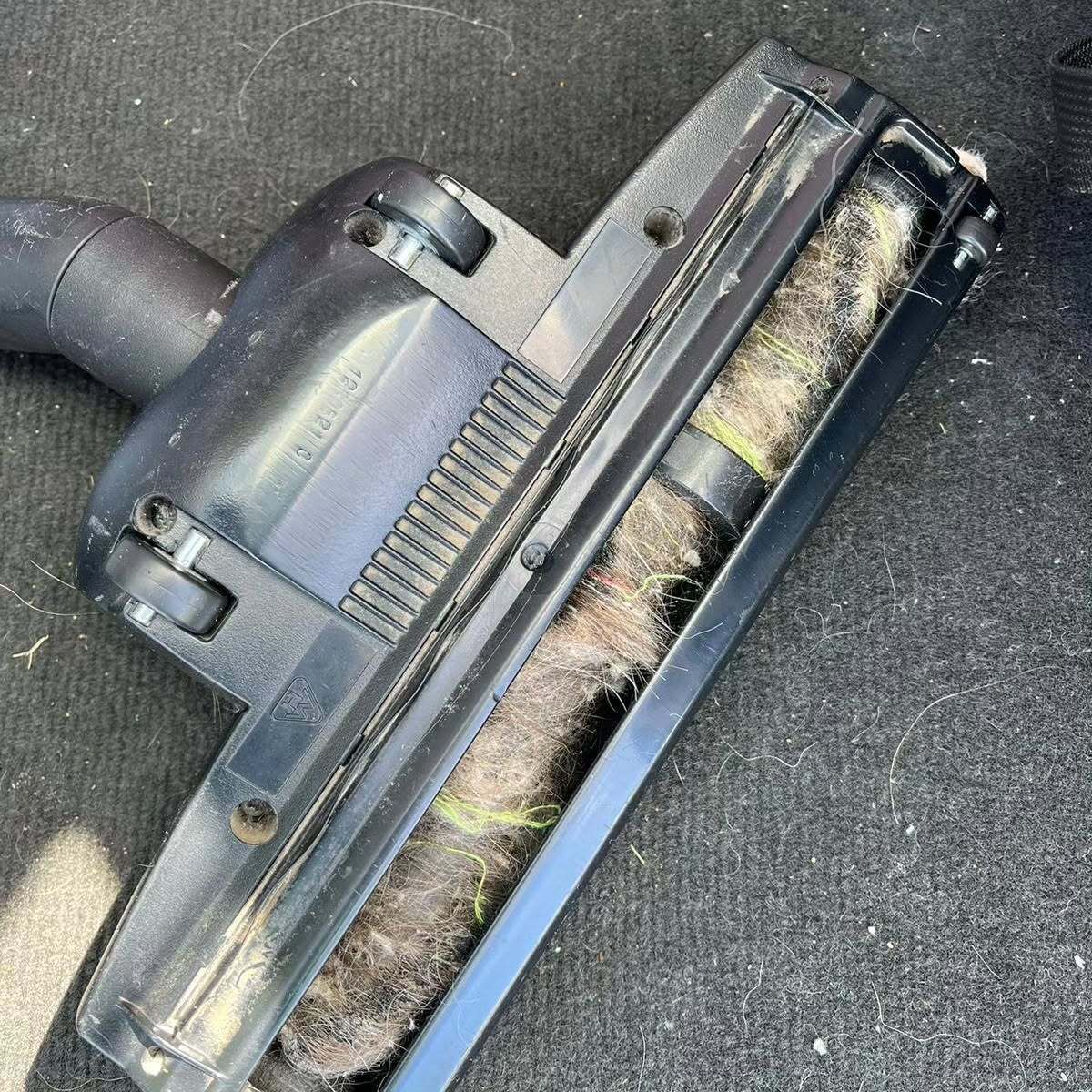A close up of a vacuum cleaner brush with a lot of hair on it.