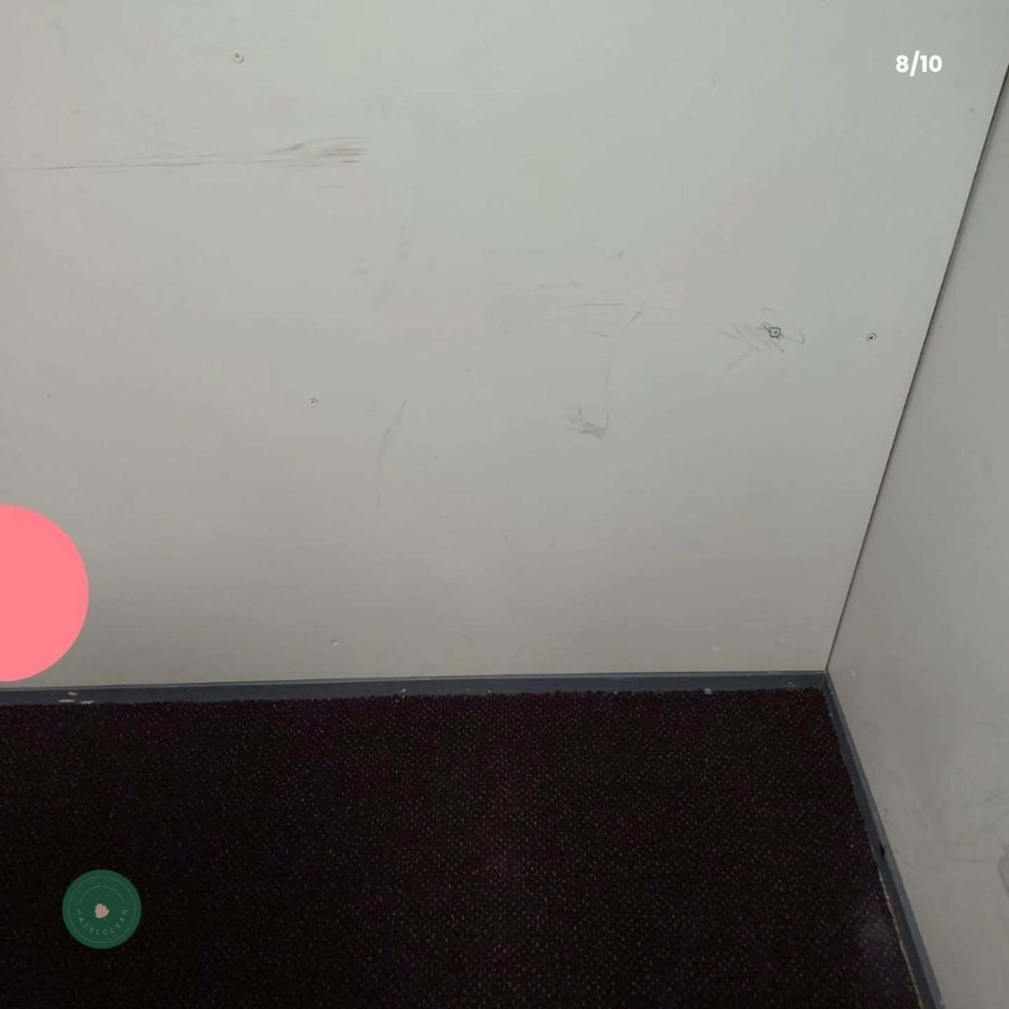 A corner of a room with a white wall and a black carpet.