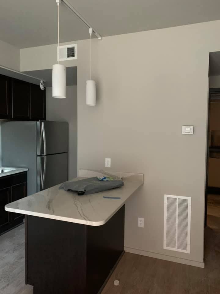 A kitchen with a marble counter top and a refrigerator