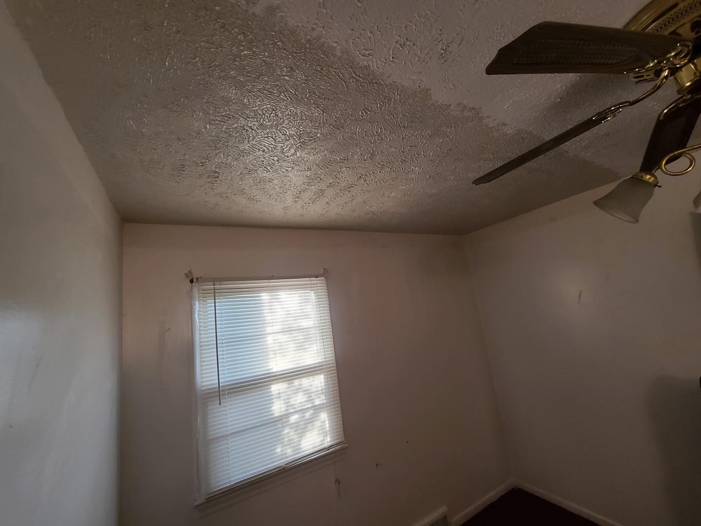 A room with a ceiling fan and a window.