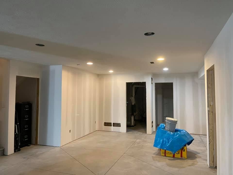 A large empty room with a blue tarp on the floor.
