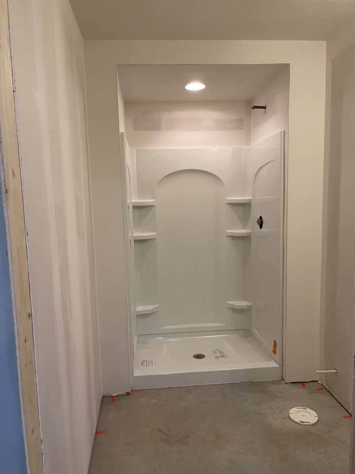 A bathroom under construction with a shower stall and shelves.