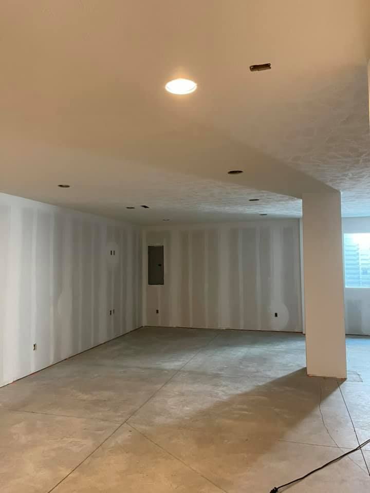 A large empty room with white walls and a concrete floor.