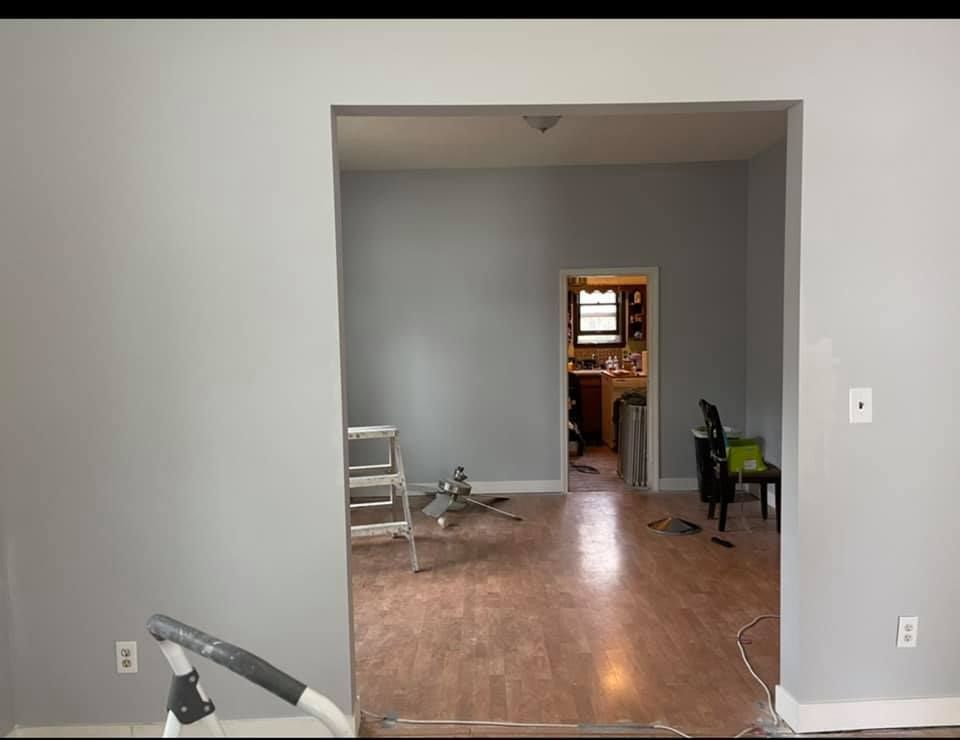 A living room with hardwood floors and gray walls is being remodeled.