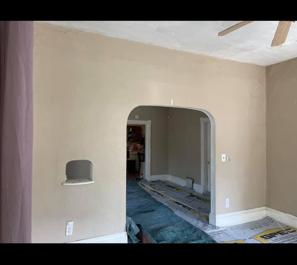 A living room with beige walls and a ceiling fan.