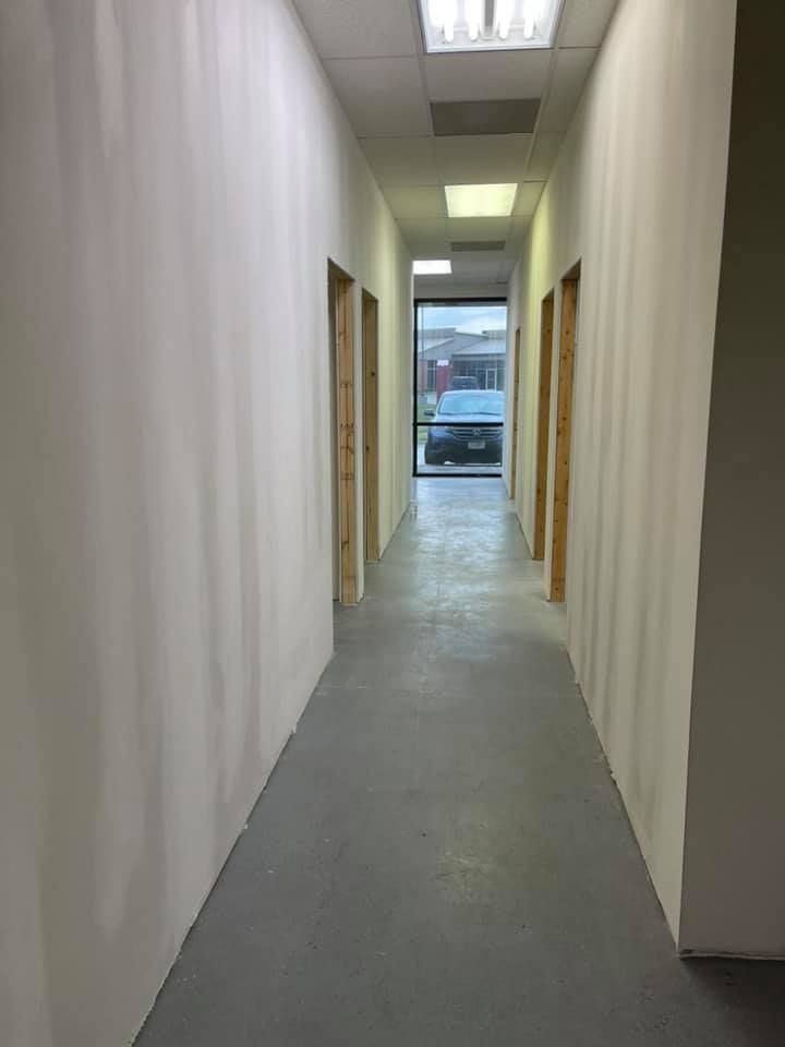 A long hallway with white walls and a concrete floor in an office building.