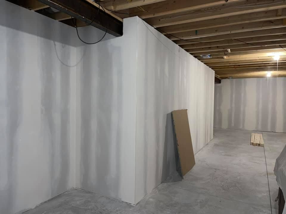A basement with drywall walls and a wooden ceiling.