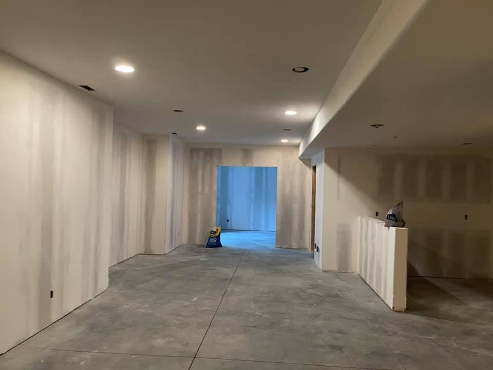 A large empty room with drywall walls and a concrete floor.