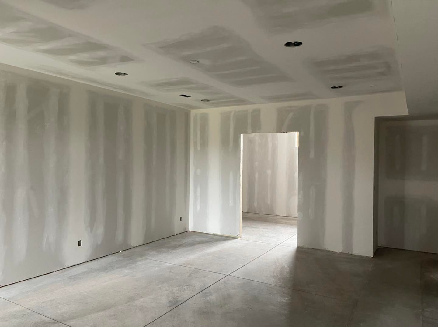 An empty room with drywall walls and a doorway.