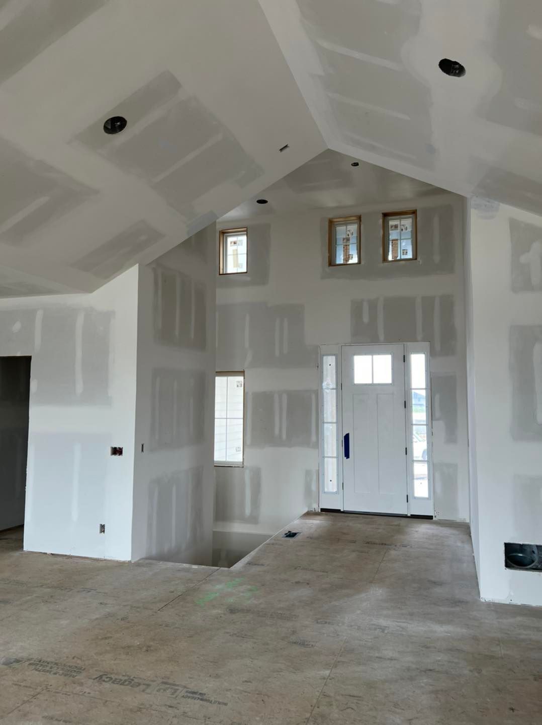 A large empty room with a vaulted ceiling and a white door.