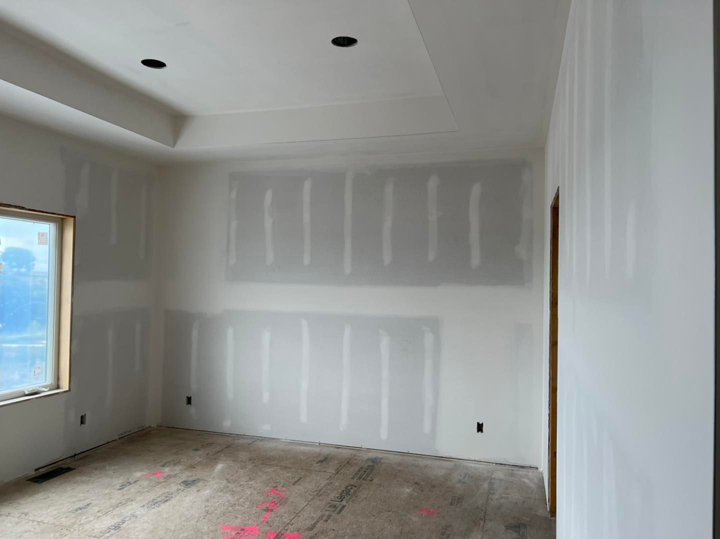 An empty room with drywall on the walls and a window.