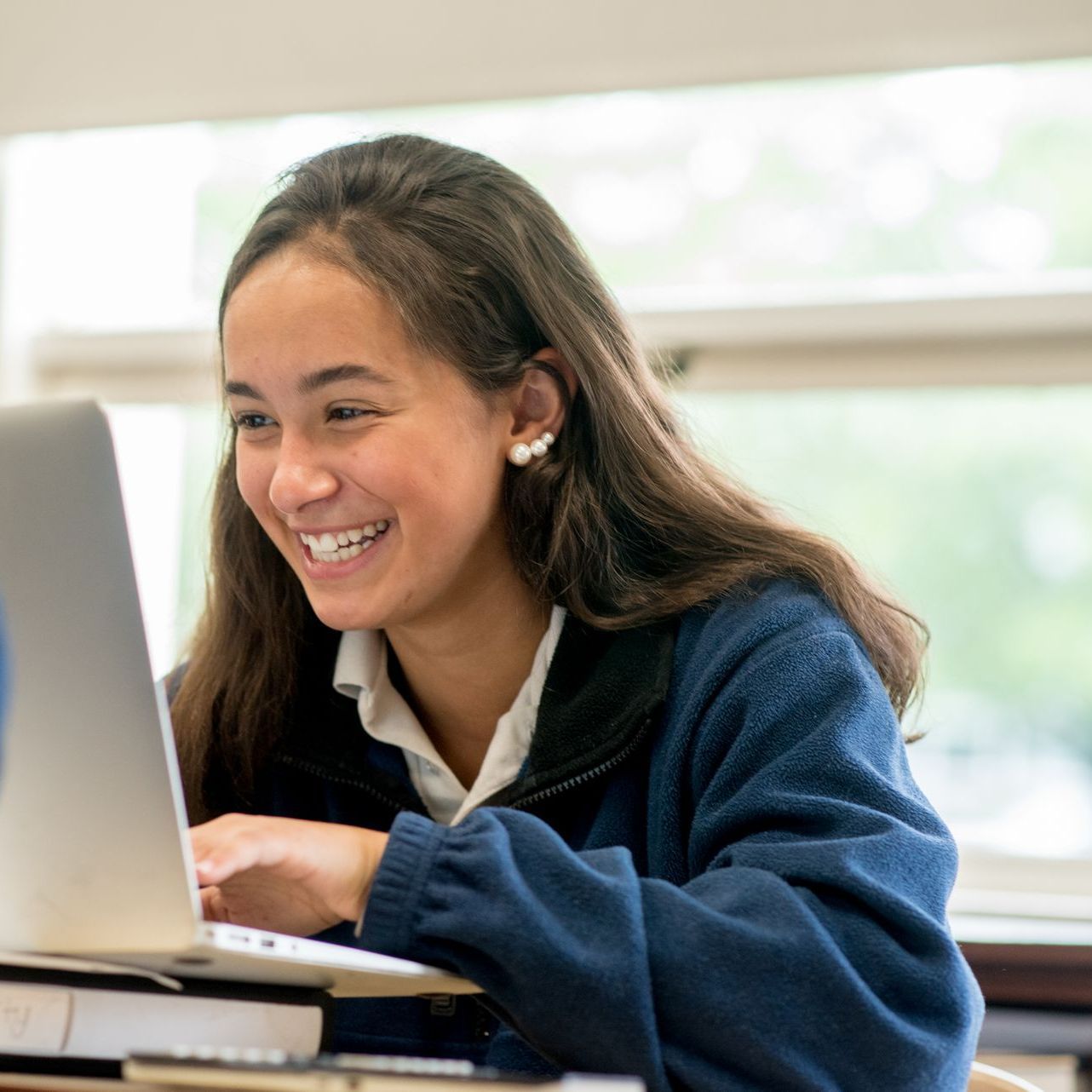 A woman is smiling while using a laptop computer