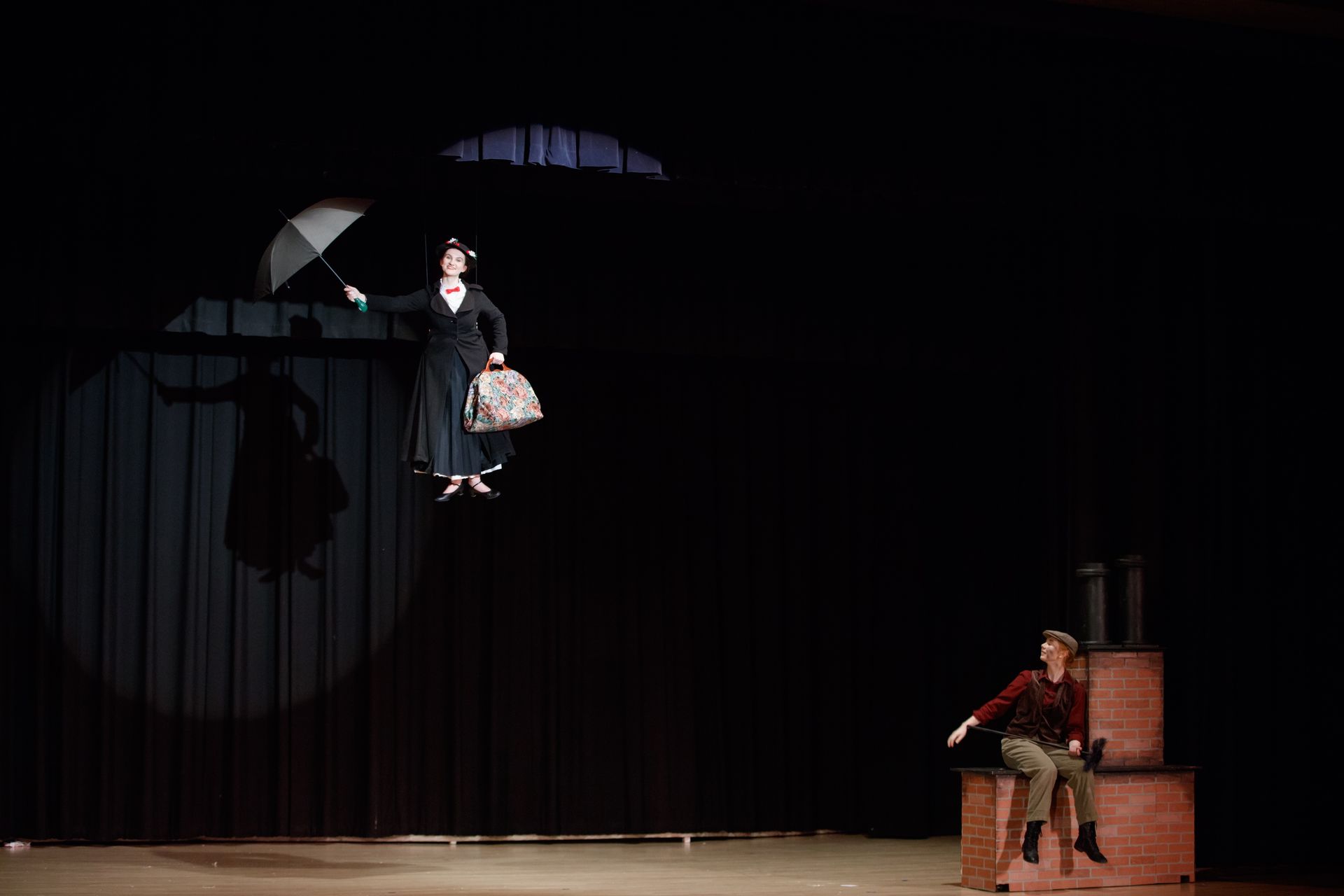 mary poppins is flying through the air while a man sits on a box