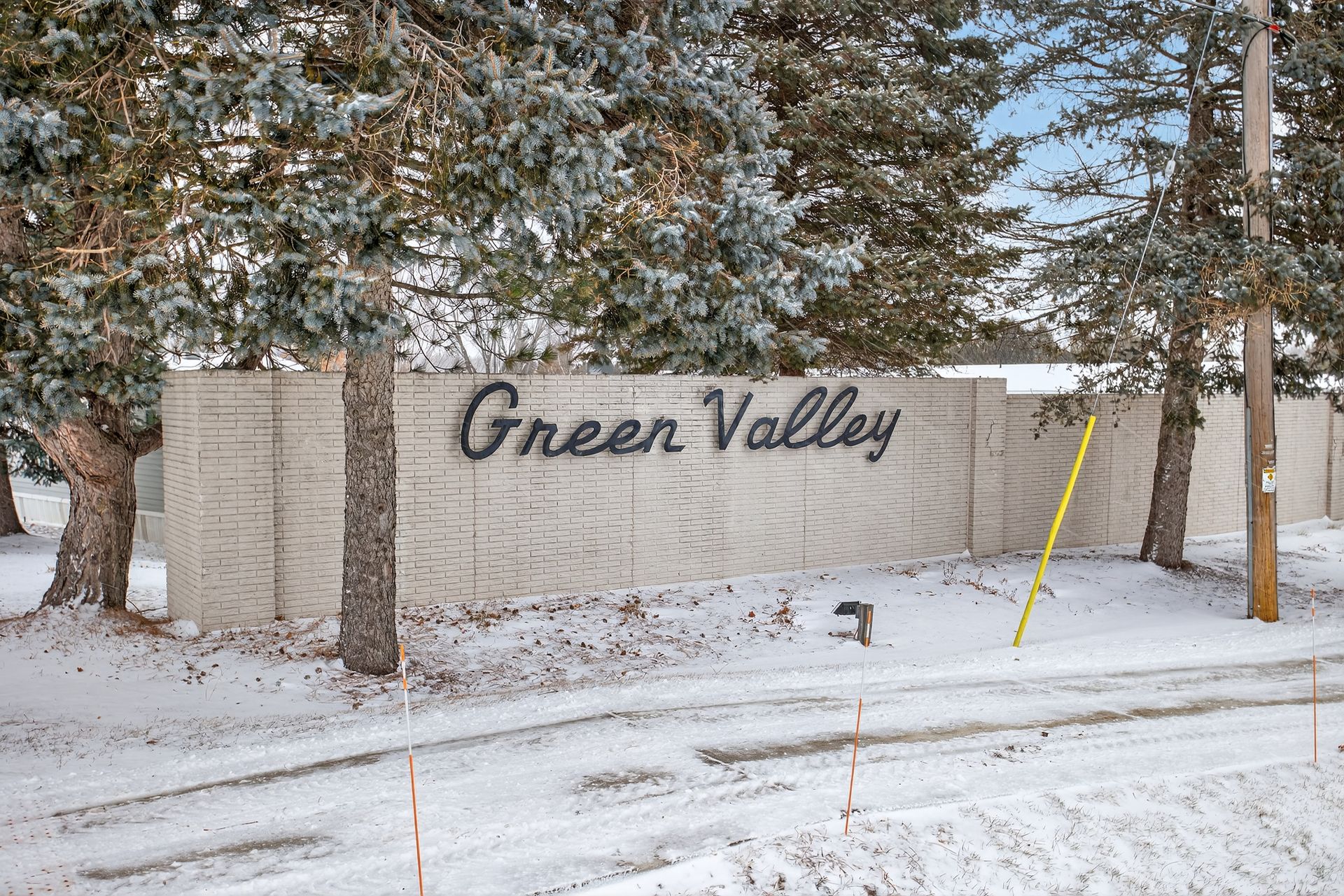 Sign for Green Valley residential area in winter, with snow and trees.