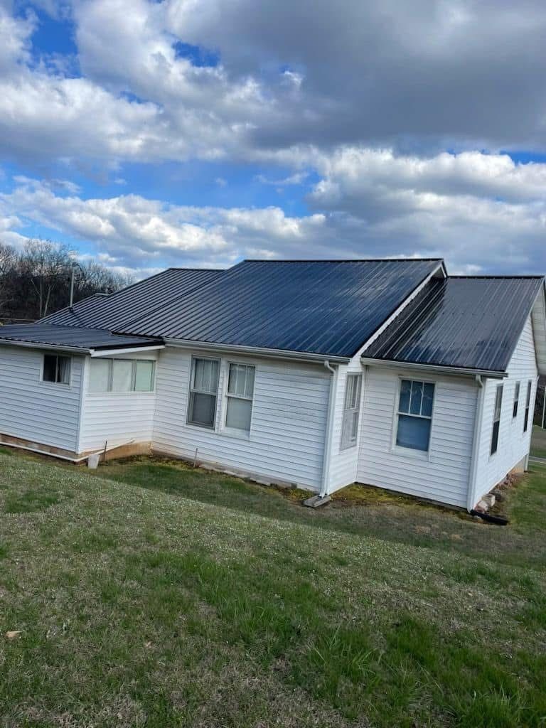 Gray brick house with a white truck parked in the driveway. Green trash bin beside the garage.