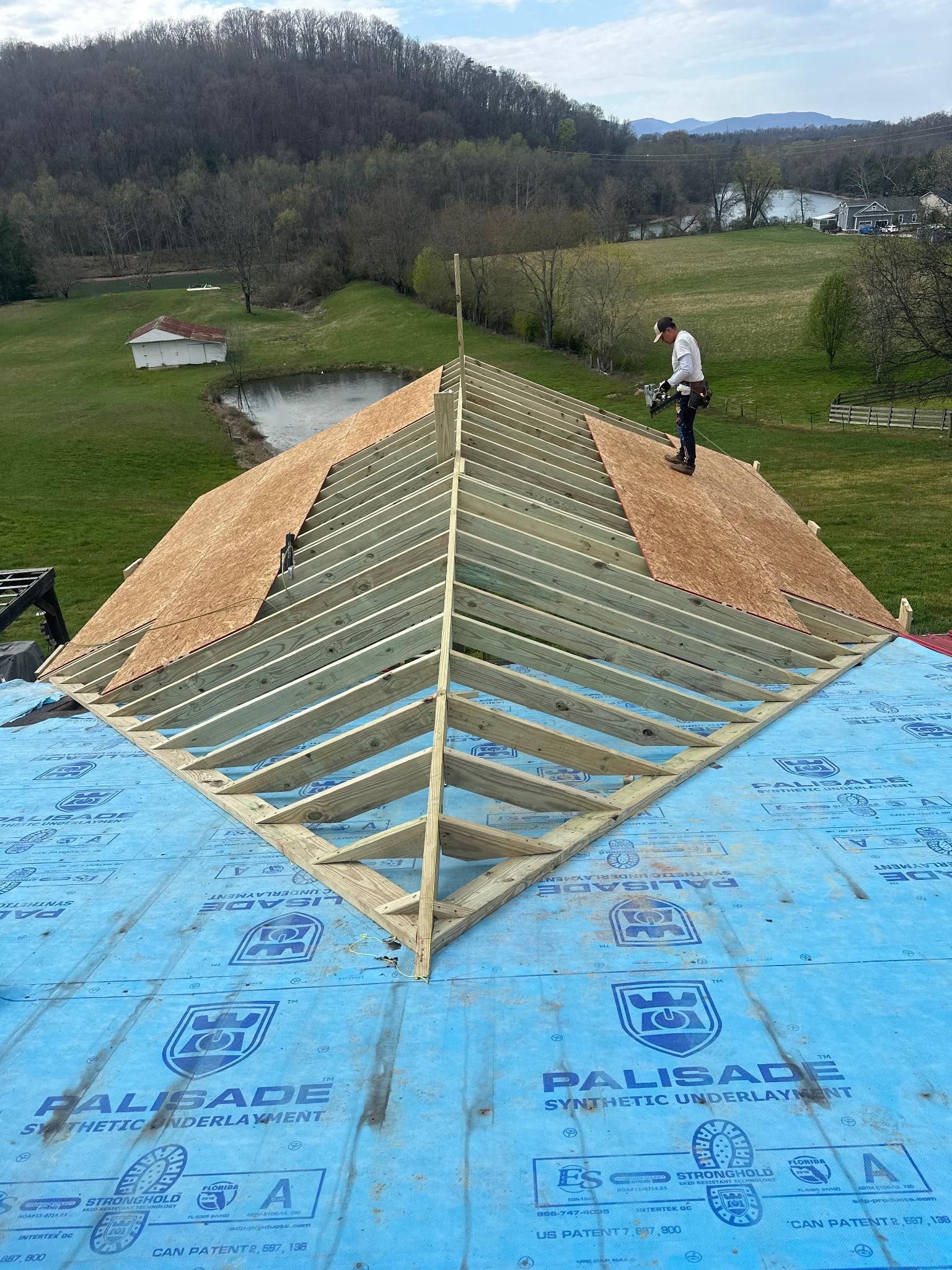 House with damaged roof; white truck parked in front. Landscaping in yard.