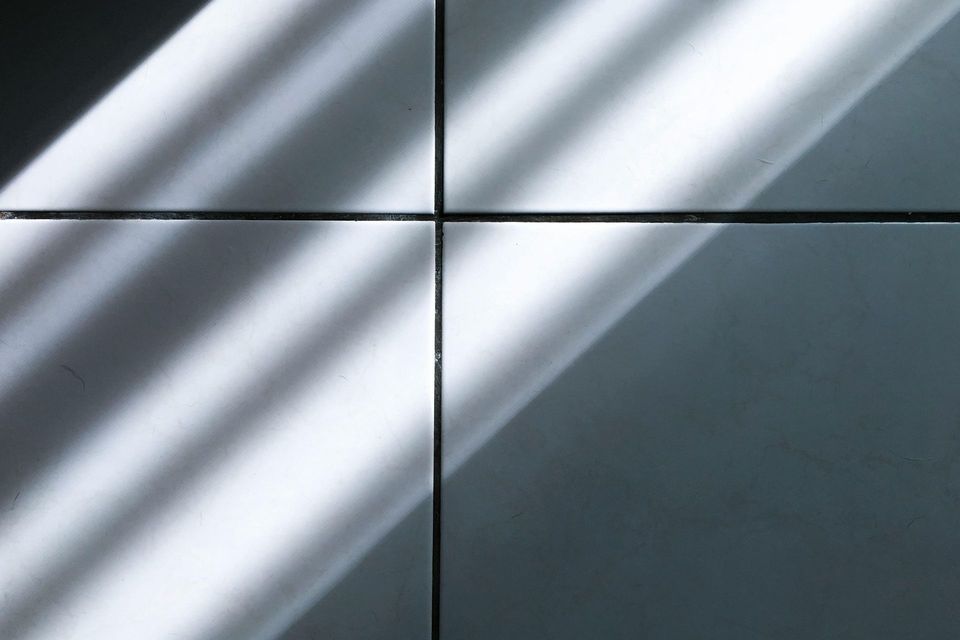 A close up of a wall with a shadow of a window on it.