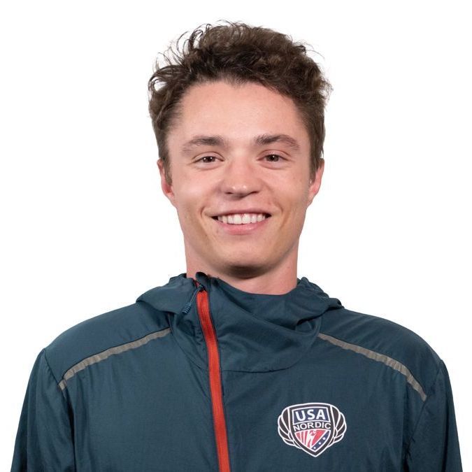 A young man wearing a  jacket smiles for the camera