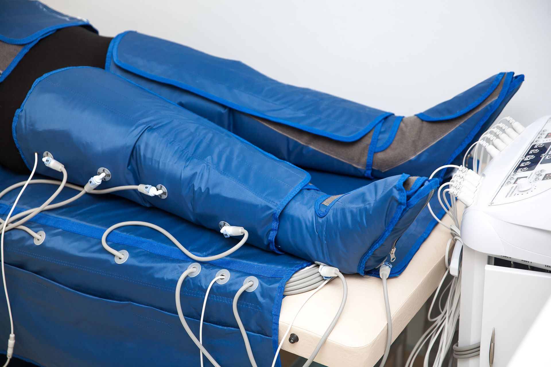 Person in blue compression leg sleeves connected to a machine.