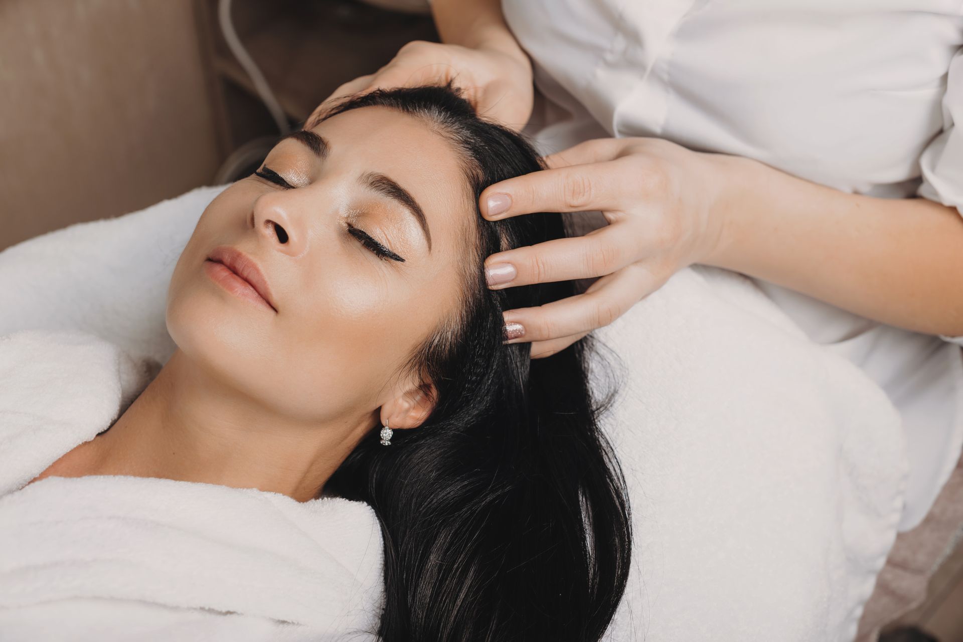Person receiving scalp massage, eyes closed, hands on head.