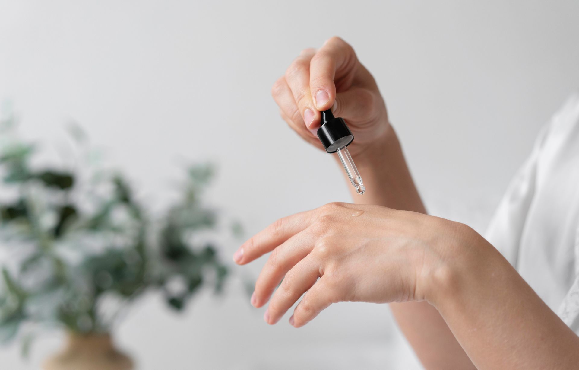A woman is applying a serum to her hand with a pipette.