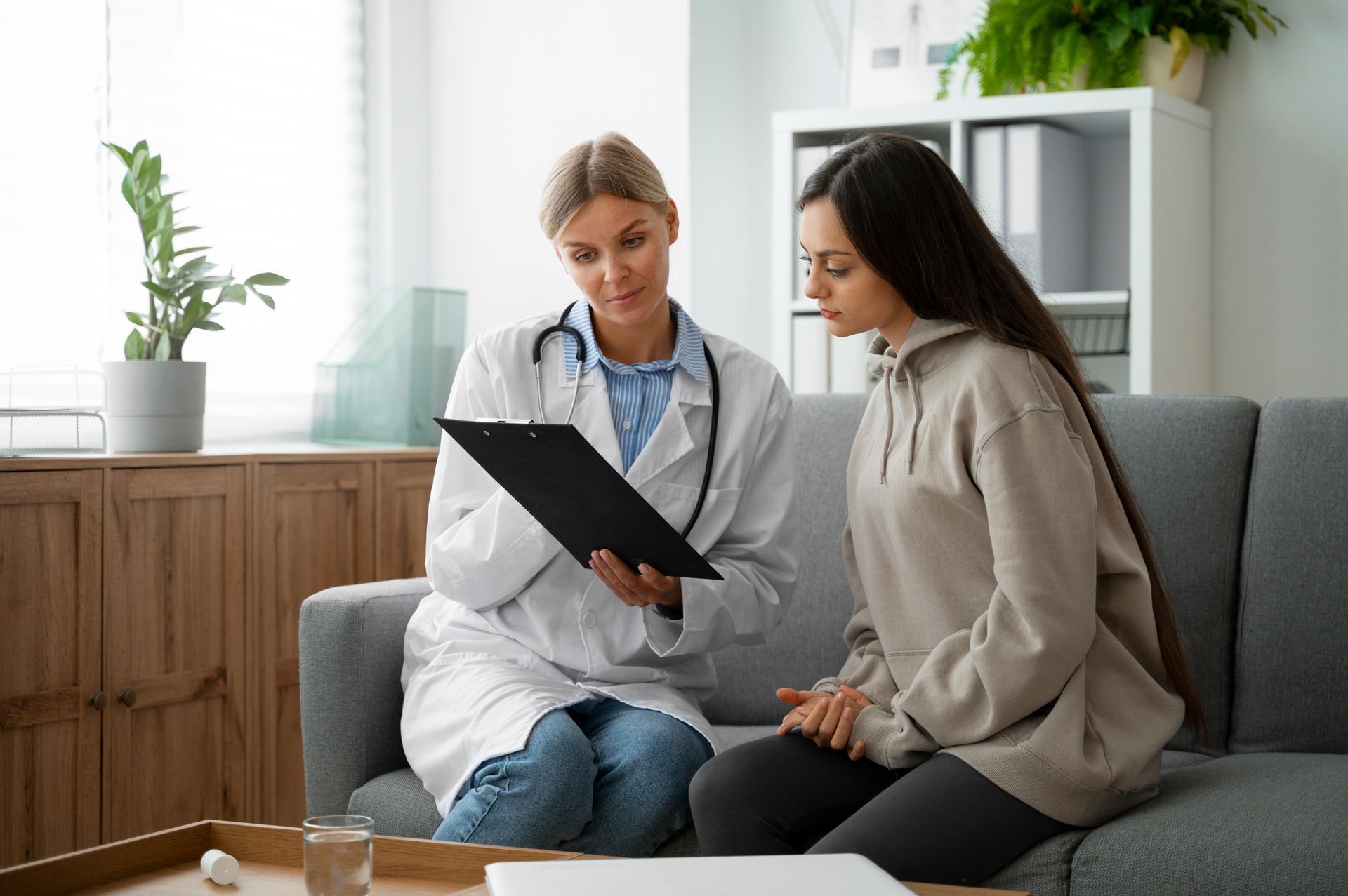 A doctor is talking to a patient while sitting on a couch.