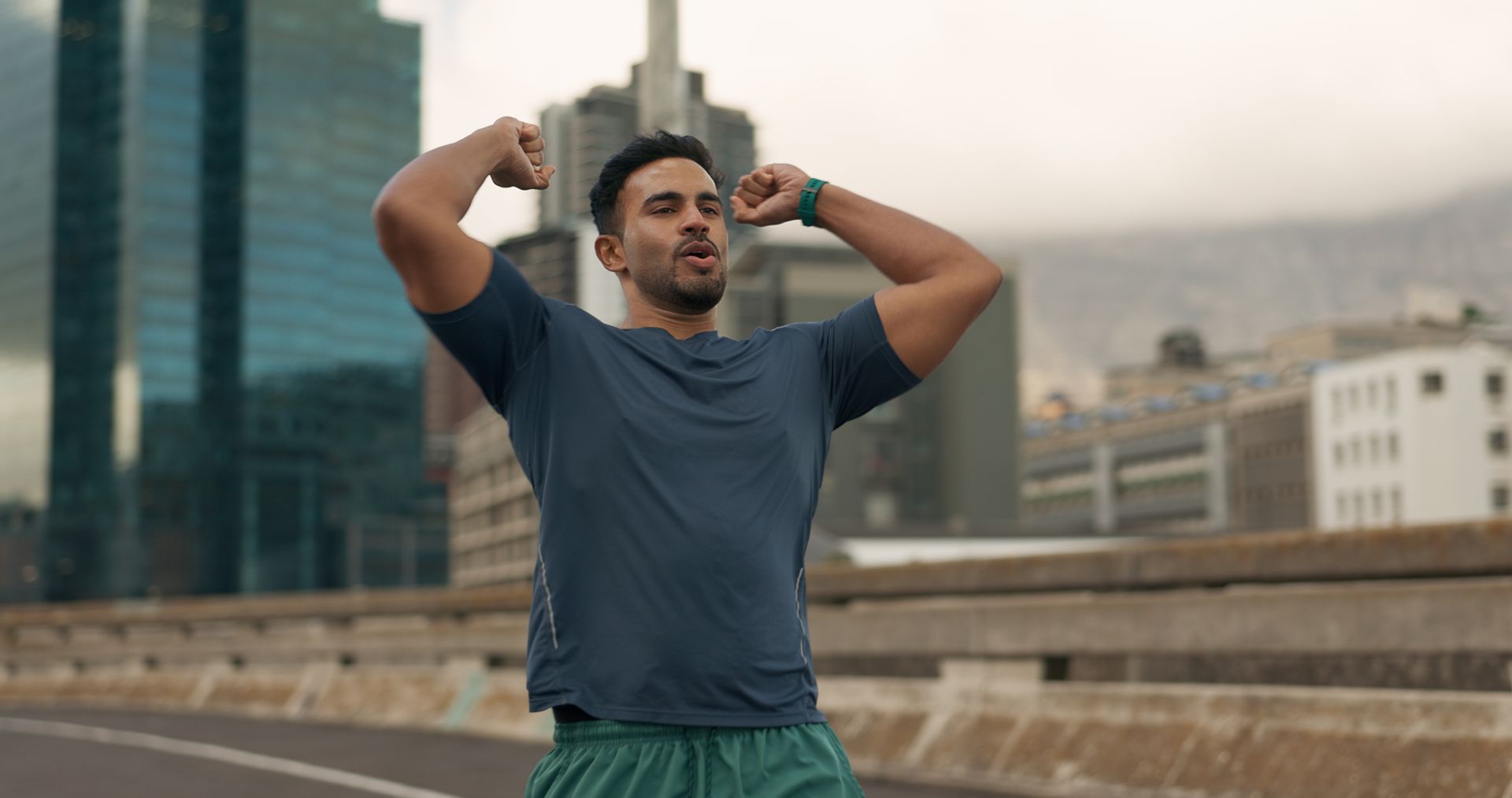A man is stretching his arms in front of a city skyline.