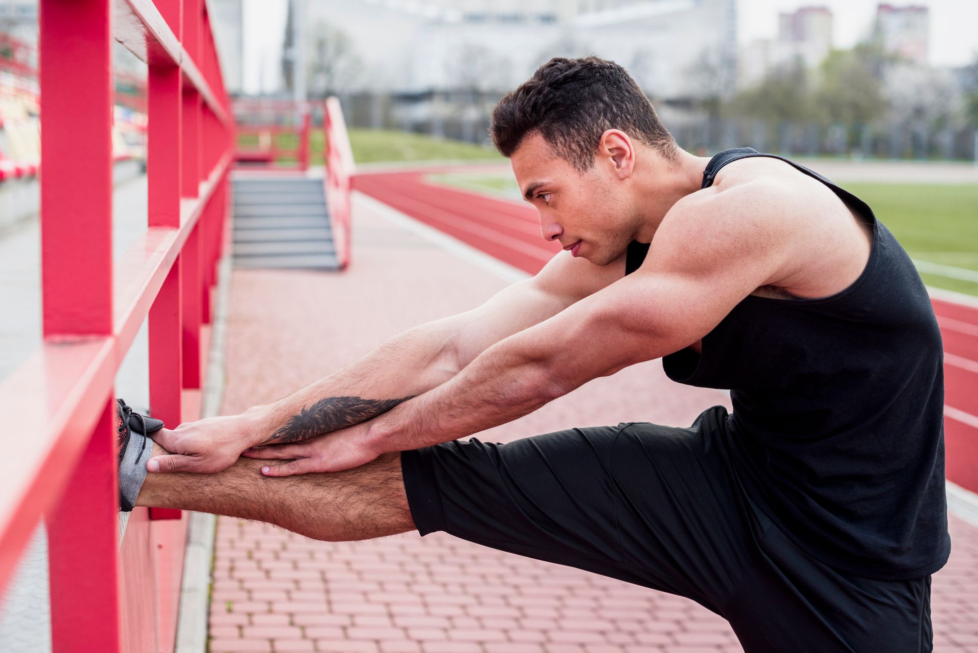 A man is stretching his legs on a brick sidewalk.