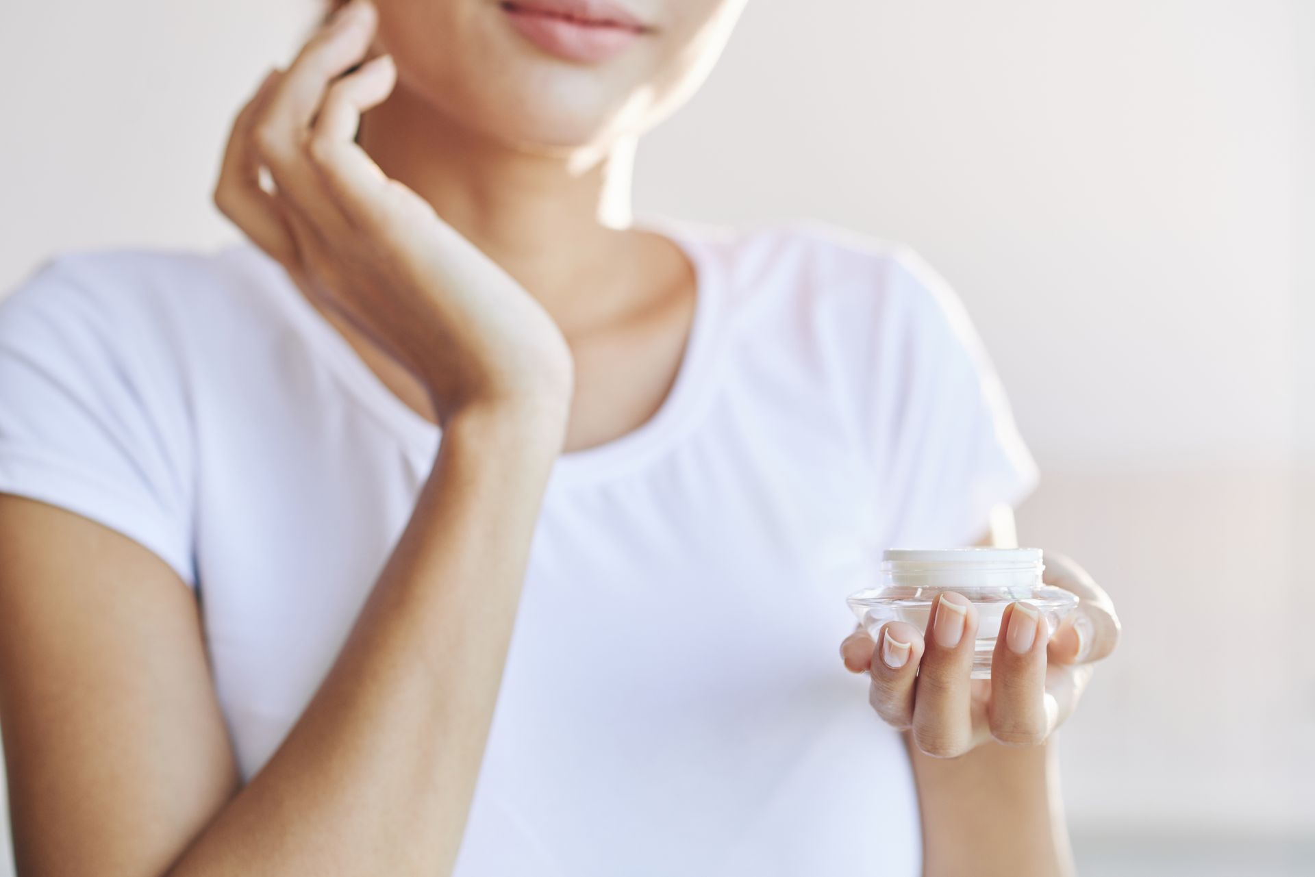 A woman is holding a jar of cream in her hands.