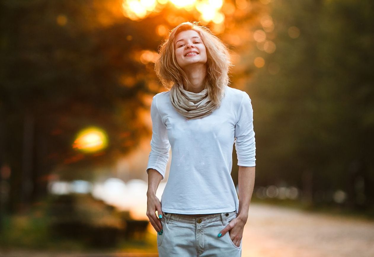 A woman is walking down a path in a park at sunset.