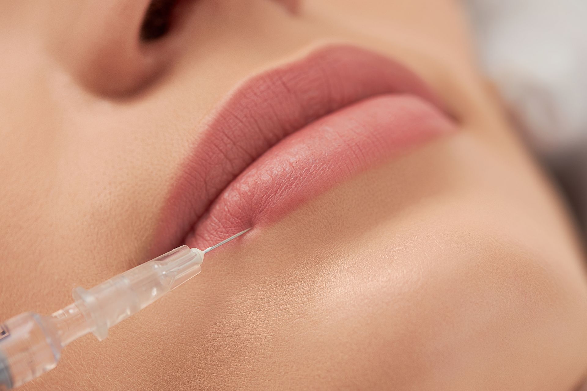 A woman is getting a botox injection in her lips.