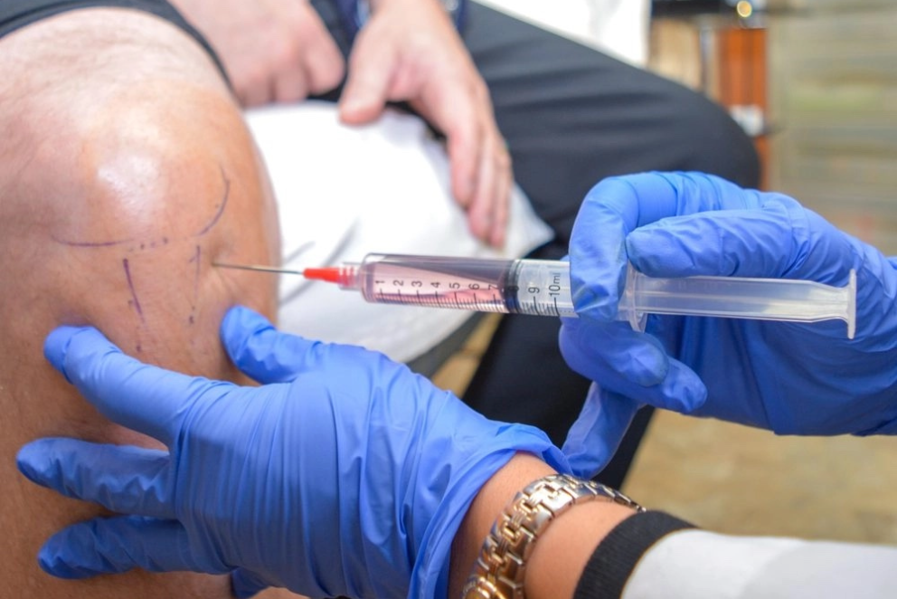A person is getting an injection in their knee.