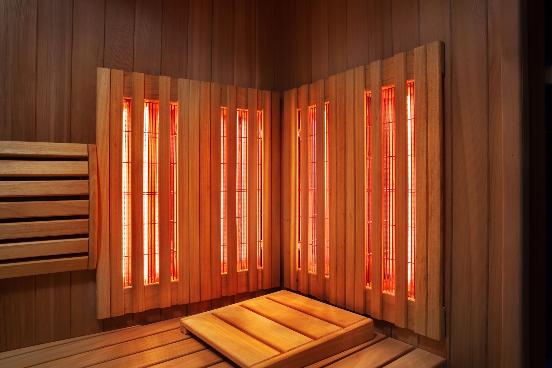 Interior view of a sauna with wooden walls and glowing infrared heaters.