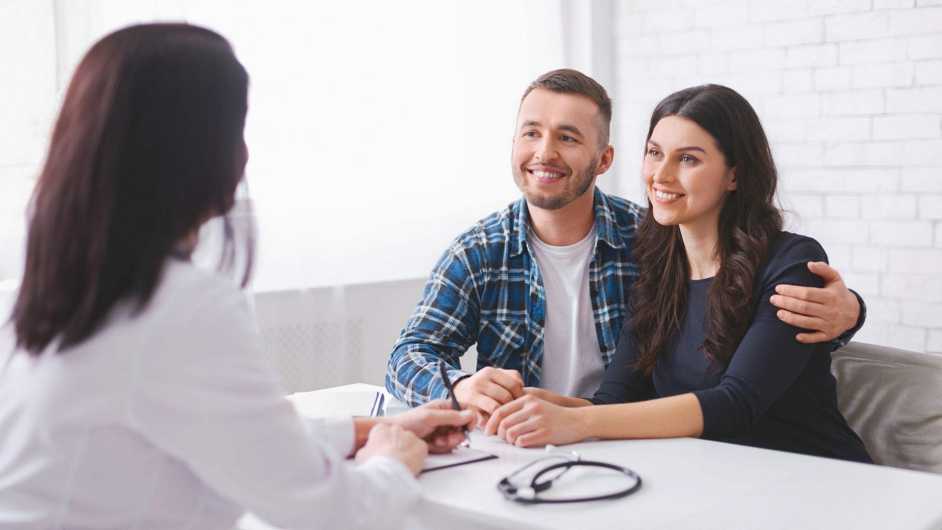 A man and a woman are sitting at a table talking to a doctor.
