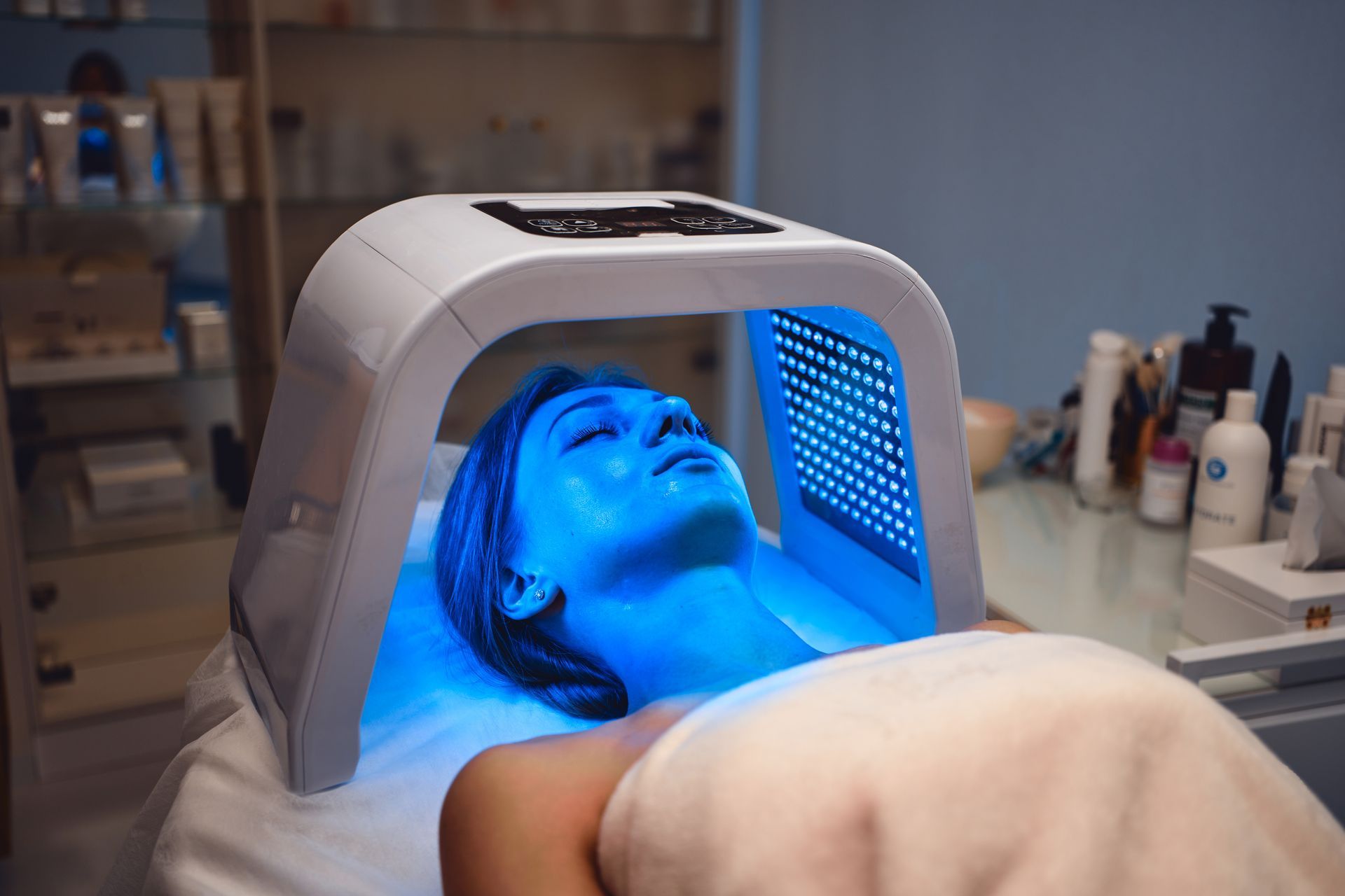 A woman is getting a blue light treatment on her face.