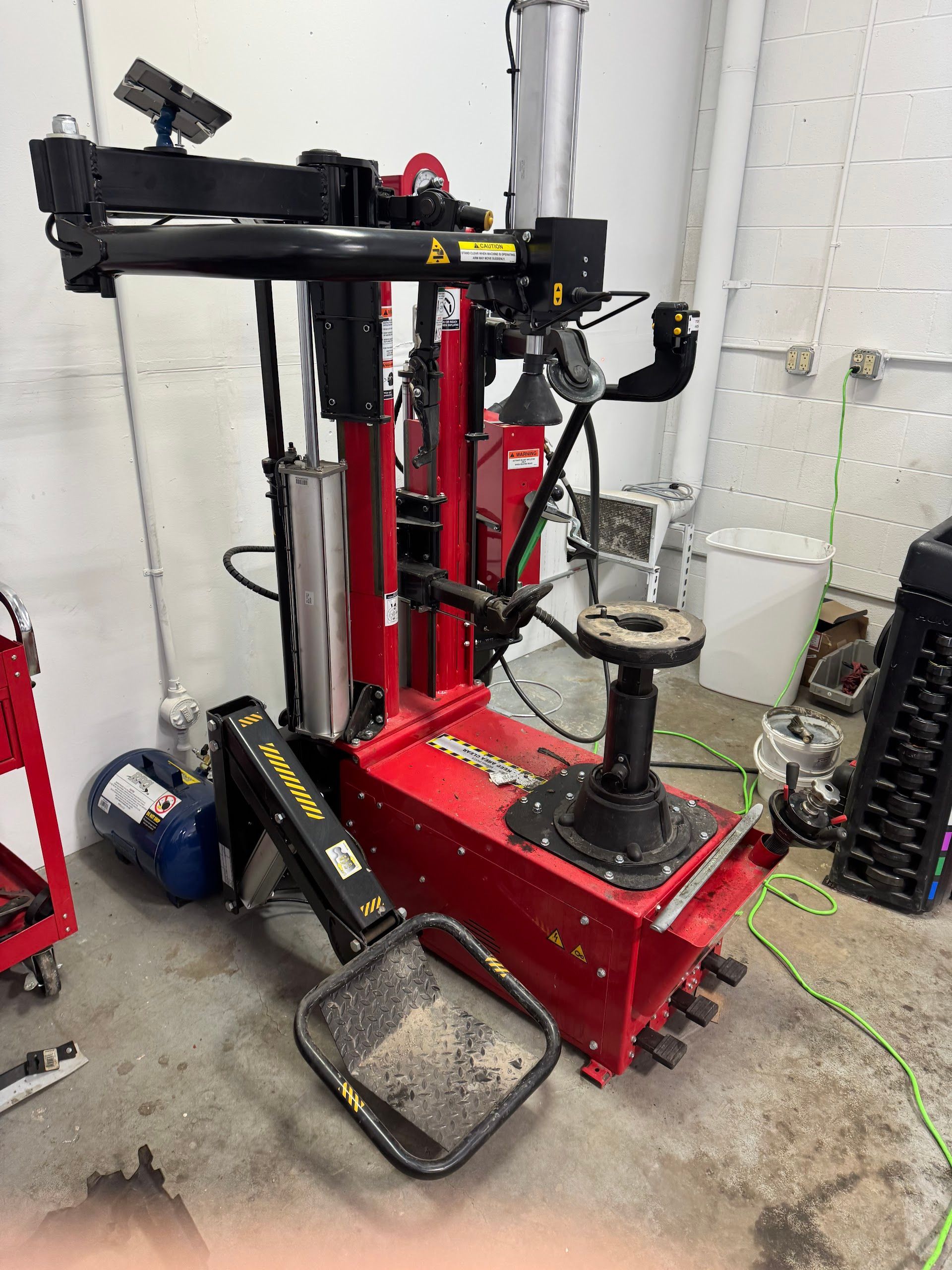 Red and black tire changing machine in a garage setting. | Auto Medics