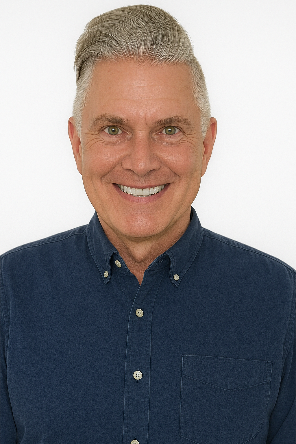 Man with graying hair smiles, wearing a blue button-down shirt against a white background.
