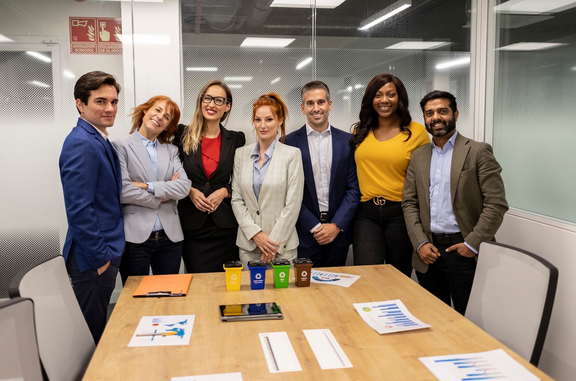 Business team of seven smiles in a conference room.